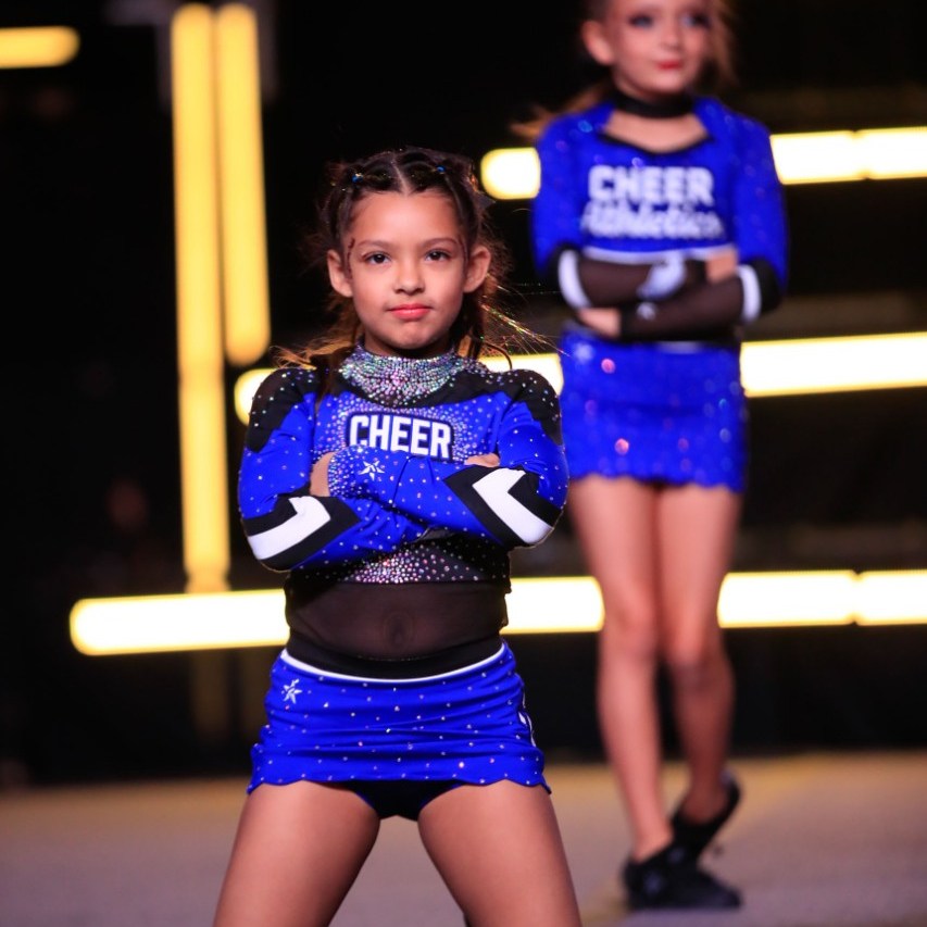 Young Cheer Athletics athlete posing confidently in uniform during a cheer performance event.